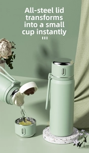 Detailed view of mint green stainless steel thermos flask pouring water into the lid cup