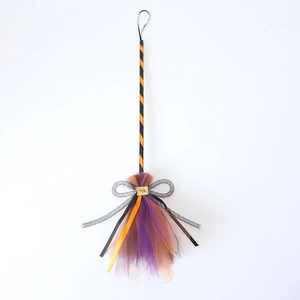 Detail of Halloween witch broom with orange striped handle and purple mesh tinsel bow