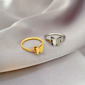 Detailed view of gold and silver butterfly rings on gray silk fabric background