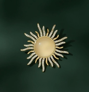 Detailed view of sun-shaped brooch featuring yellow cat eye stone and cubic zirconia inlay