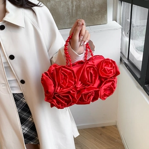Detail of red rose-shaped evening bag featuring satin flowers and beaded top handle