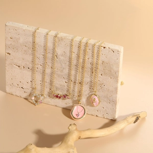 Detail view of four 14K gold plated necklaces featuring pink zircon and enamel pendants