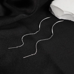 Minimalist silver wave chain earrings for women displayed on a black textured background