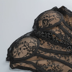Dettaglio di un corsetto in pizzo nero con ricamo floreale e lacci incrociati sul davanti