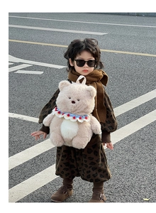 Outdoor shot of a toddler wearing a leopard print tracksuit with a plush bear backpack