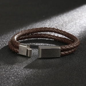 Detail of a brown woven leather bracelet with a magnetic stainless steel clasp in luxury lighting
