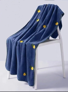 Detail of soft dark blue coral fleece towel with yellow pineapple embroidery on chair