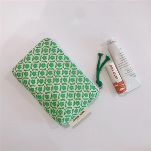 Macro detail of floral cotton mini pouch with white zipper and green woven pull tab