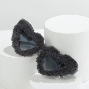Gray plush heart shaped sunglasses with dark lenses on a geometric display stand