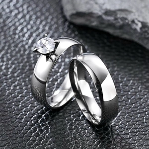 Detail of silver couple rings set featuring a four-prong solitaire and plain metal band