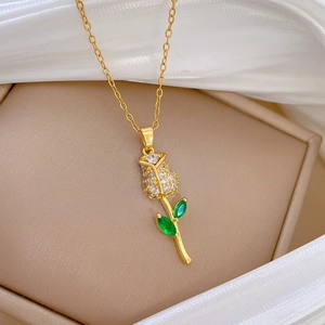 Luxurious gold rose necklace with clear crystals and green zircon on a white silk background
