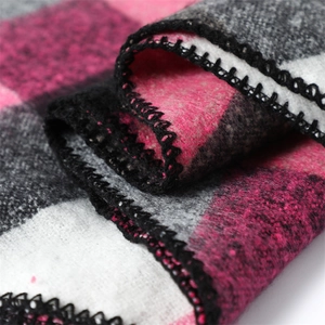 Macro detail of plaid cashmere scarf showing soft texture and neat black edge stitching