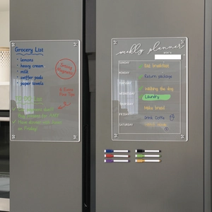 Detail of magnetic acrylic weekly planner and grocery list set on a grey refrigerator