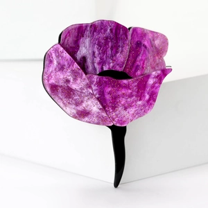 Detail view of purple acrylic rose hair clip with glitter petals on white background
