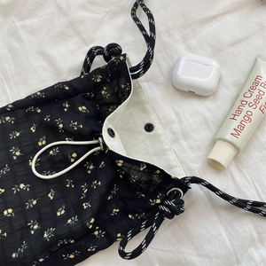 Detail view of floral canvas crossbody bag with drawstring closure and metal eyelets