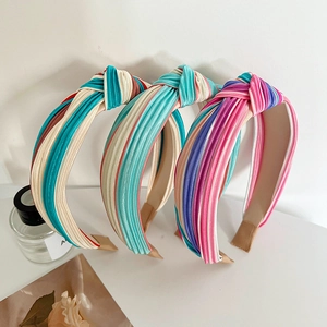 Detailed view of three knotted headbands in multi-colored striped pleated fabric textures