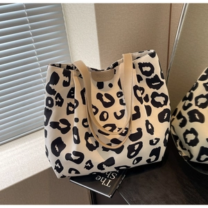 Détail du sac cabas en toile léopard avec bandoulières beiges et étiquette de marque Boons