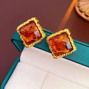 Detail of amber resin square earrings with textured gold-tone metal frame in vintage style