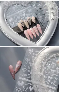 Detailed macro view of 3D embossed white bow and pearl nail art stickers for French manicures