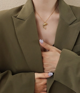 Close-up of a 18K gold plated dolphin pendant on a fine chain worn by a model