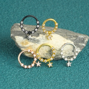 Detailed view of five colorful stainless steel nose rings with stars on a natural stone