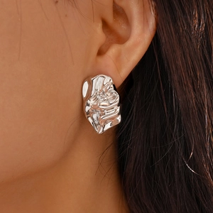 Detail of silver irregular crumpled lava earrings worn by model with metallic texture