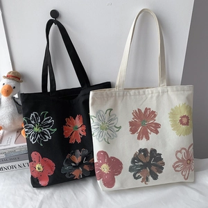 Detail of cotton canvas tote bags in black and beige with colorful abstract floral prints