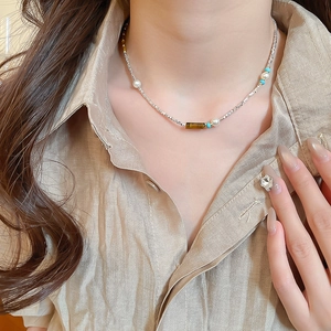 Close-up of tiger eye stone and pearl beaded necklace worn on a woman's neck
