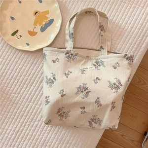 Flat lay of vintage floral cotton handbag with zipper and simple wish label
