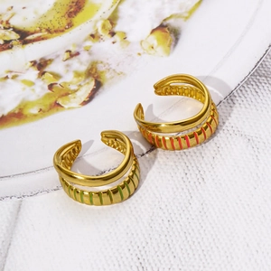 Close-up of golden dual-layer rings featuring green and pink enamel striped textures