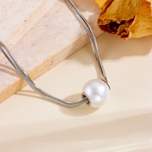 Double-layered silver snake chain necklace with a large white pearl pendant on stone