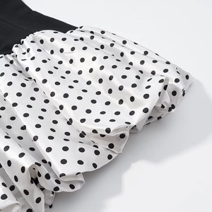 Detailed view of the black V-neck bodice and white polka dot pleated satin skirt