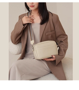 Detail view of beige lychee texture crossbody bag with wide striped fabric shoulder strap