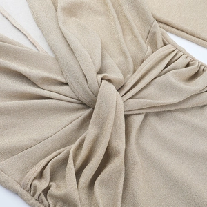 Detailaufnahme von champagner-goldenem Glitzerstoff und dem vorderen Knotendesign am Kleid