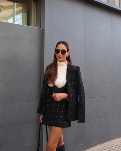 Gros plan sur la broderie fraise d'un ensemble blazer et jupe trapèze pour femme