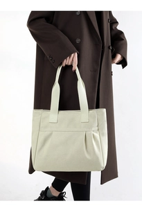Close-up of minimalist beige canvas tote bag with front pocket and pleated details