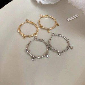Detailed macro view of spiked hoop earrings with star charms in gold and silver plating