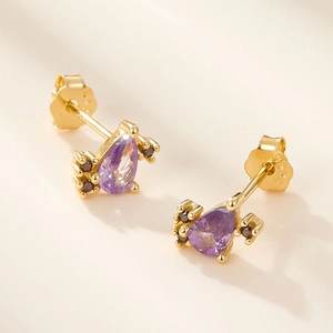 Macro shot of S925 silver stud earring with purple pear-cut zircon and golden plating