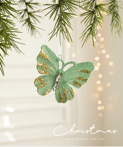 Close-up of mint green Christmas butterfly ornament with gold sequins on tree branch
