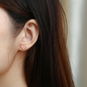 Orecchini a perno minimalisti a cuore rosa con diamante sull'orecchio della modella