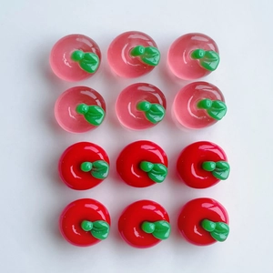 Detailed view of red and pink resin apple charms for DIY crafts and phone accessories