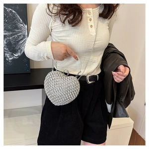 Silver rhinestone heart-shaped evening bag with metal ring handle shown on a model