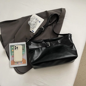 Vue à plat d'un grand sac cabas noir en cuir avec un blazer et une tablette tactile