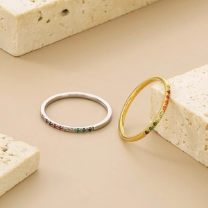 Rainbow gemstone eternity rings in gold and silver finish on elegant travertine stone