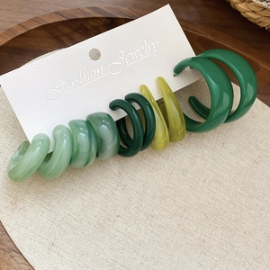 Détail d'un ensemble de cinq boucles d'oreilles en acrylique vert en forme de C sur carte