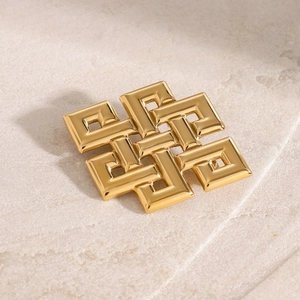 Macro di un orecchino a nodo celtico dorato con motivo geometrico traforato su pietra