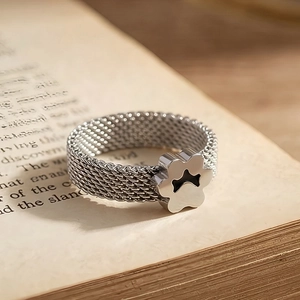 Detailed macro view of a silver mesh stainless steel ring featuring a cat paw motif on vintage paper