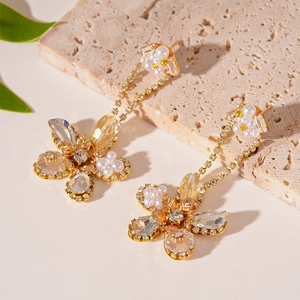 Detailed view of floral stud earrings with cubic zirconia, pearls and cascading tassels
