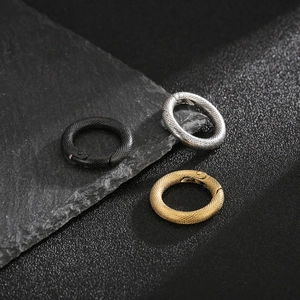 Three-color stainless steel snake rings with scale textures on a textured rock background