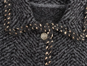 Macro detail of dark grey knit cardigan featuring sequin trim and a vintage metal button